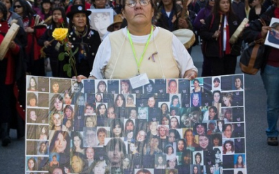 First Nations woman holding a sign of the pictures of missing and murdered indigenous women at Annual Missing Women's Memorial March
